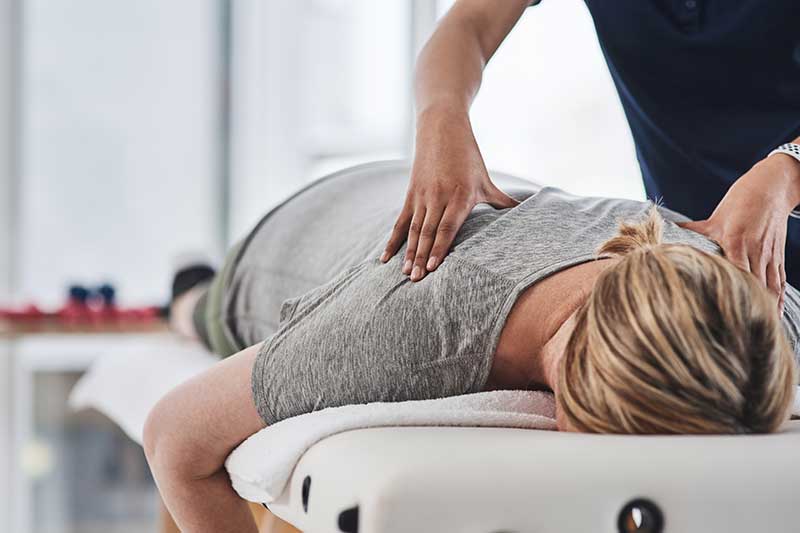 Chiropractor rubbing back of woman